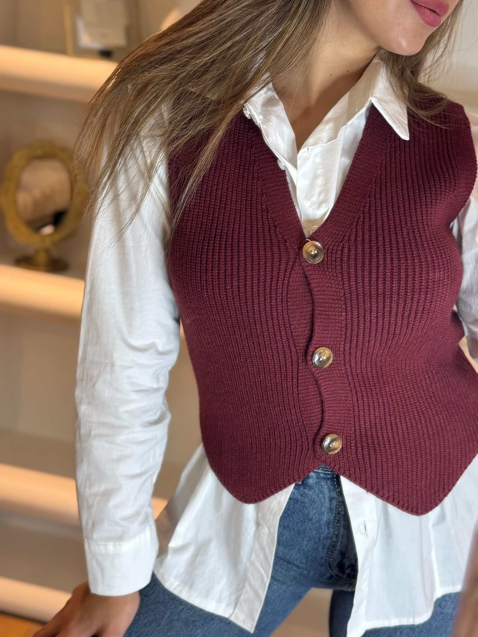 Women’s bordo knit button-front vest layered over a white shirt
